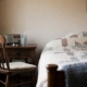 Chair pulled close to a bedside with a cup of water and a small radio on the nightstand